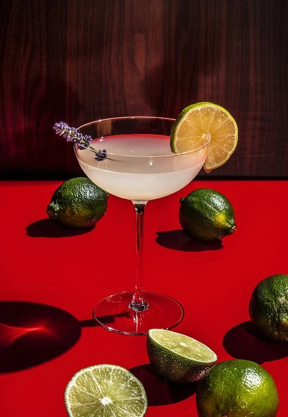 Margarita with fresh limes against a vivid red background