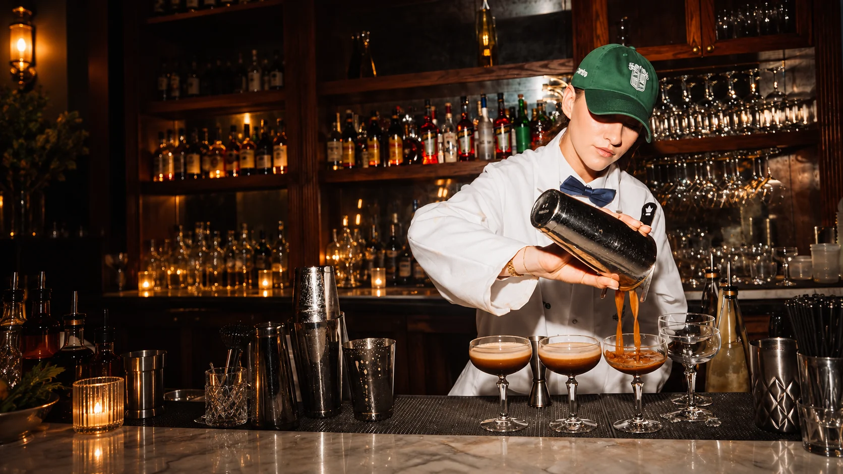 Bartender pouring three cocktails behind a professional bar