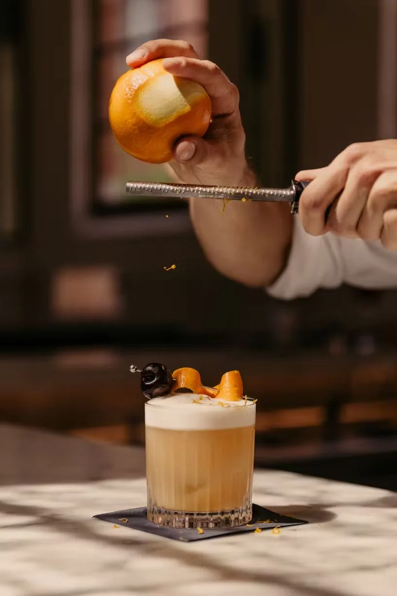 A bartender finishing a cocktail with fresh citrus